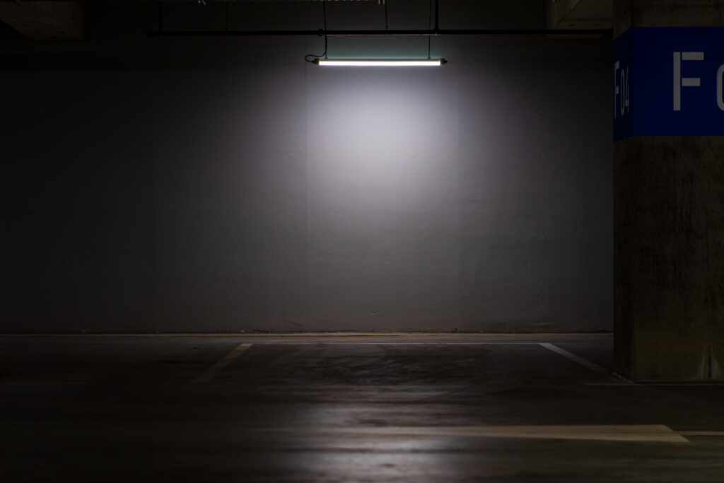 Empty parking garage lit by a single dim overhead light, illustrating inadequate lighting in a Louisiana negligent security claim