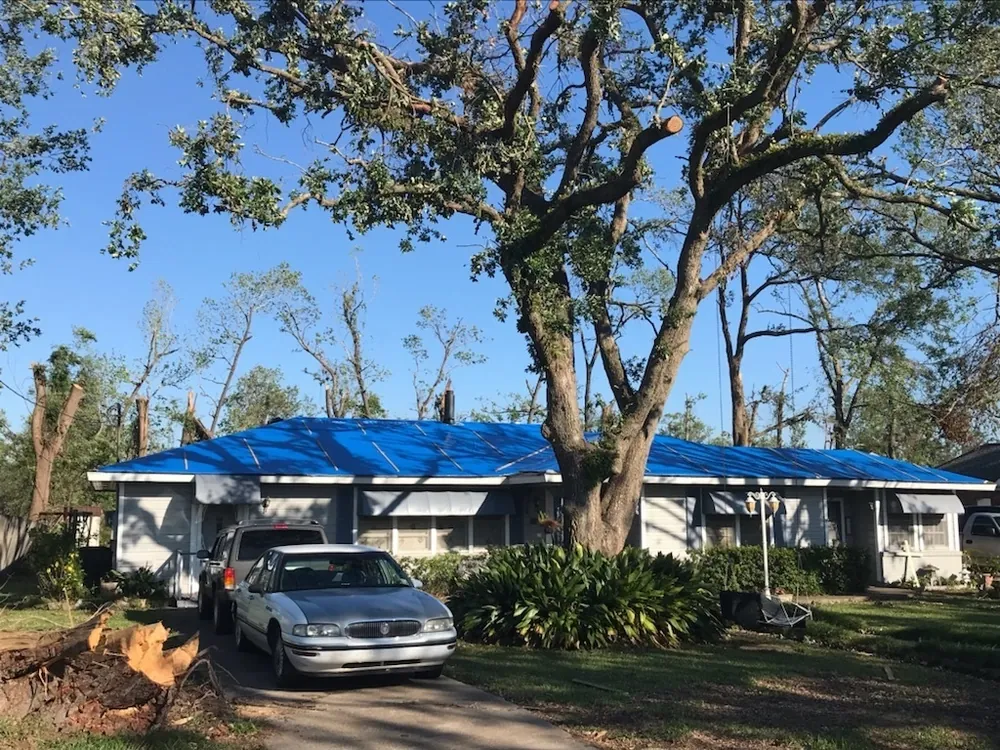 Louisiana house with a blue tarp covering the roof after a hurricane